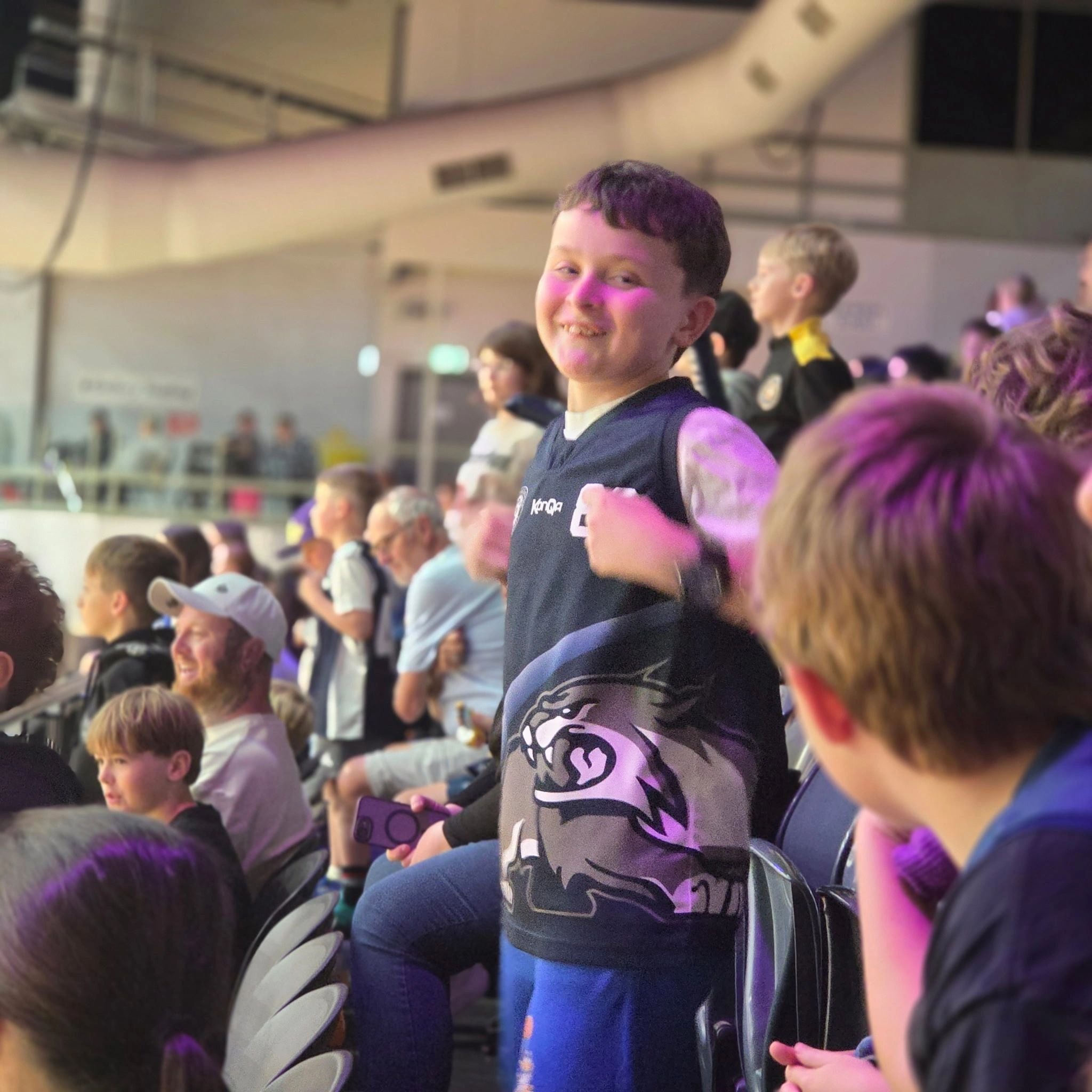 A young Bobcat in the club top cheering in the stands at Geelong Arena