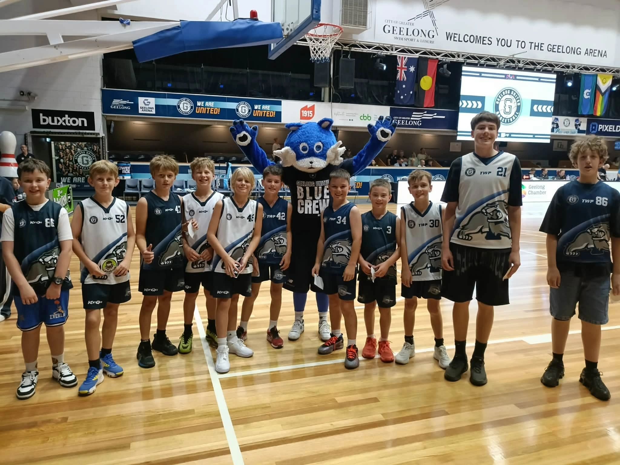 A Bobcats junior team lined up on court with the Geelong United mascot